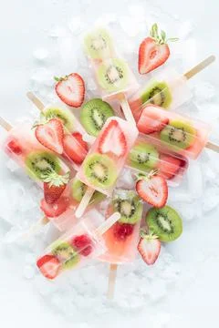 Top down view of strawberry kiwi popsicles in a pile on ice. Stock Photos