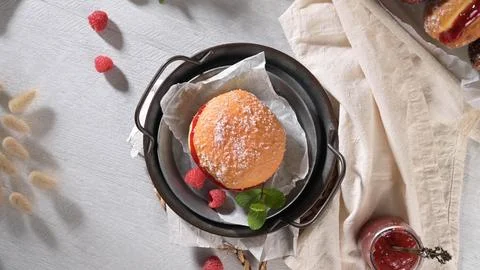 Top down view of a sugar dusted jam filled donut with fresh raspberries in .. Stock Photos