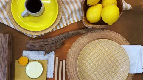 Top-down view of a summer table setting in progress. Bright yellow tableware and 動画素材 311847509