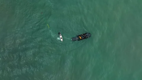Top-down view of surfer holding tow rope behind jet ski Stock Footage 309001642