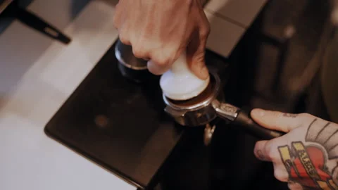 Top-Down View of Tattooed Hands Tamping Coffee in Filter Basket Stockbeeldmateriaal 307583365