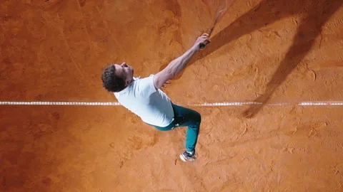 Top-down view of a tennis player serving a ball on a clay court. Concept of Stock Footage 288809070