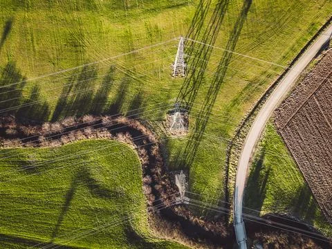 Top down view of three electrical towers standing on fields in the countryside Stock Photos