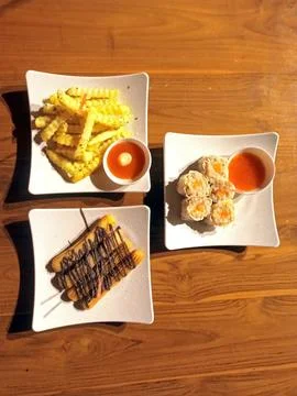 Top-down view of three square plates of different foods Stock Photos