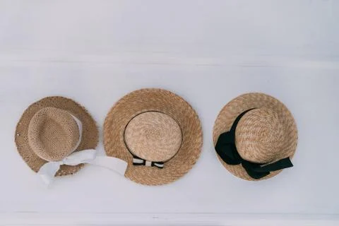 Top down view of three straw hats with bows on white background Stock Photos
