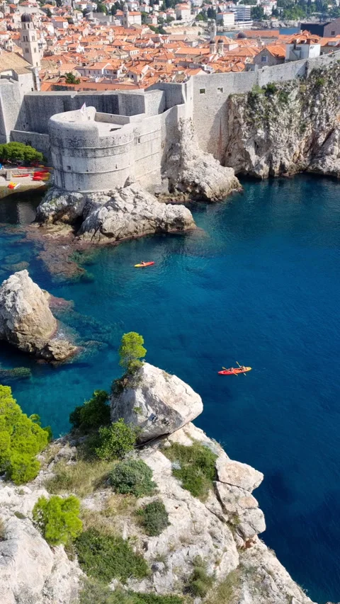 Top down view of tourists paddling in kayaks near the fortress cliff, Dubrovnik. Stock Footage 335796354