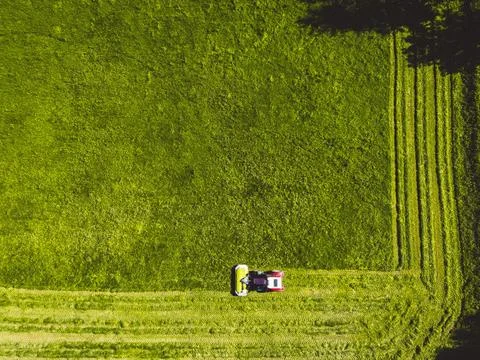 Top down view of a tractor mowing a grass field in straight lines all around Stock Photos