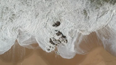 Top down view of turbulent white waves crashing on rocks on beach Stock Footage 95171145