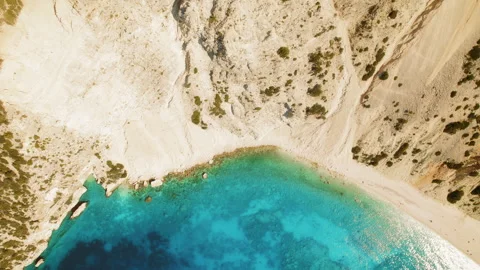 Top down view of turquoise bay and sandy beach surrounded by rocky cliffs in Stock Footage 309584294