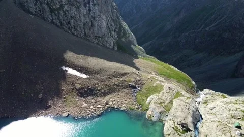 Top down view of turquoise lake edge and waterfall in rocky mountain gorge Vidéo 334326531