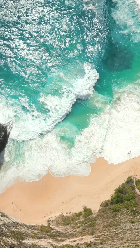 Top-down view of turquoise ocean waves crashing on remote beach and cliffs Bali Stock Footage 307313526
