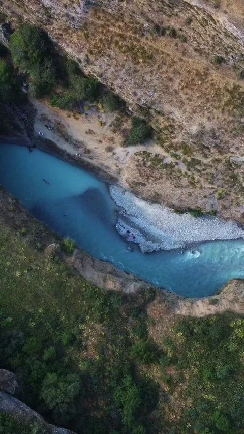  Top down view of turquoise river flowing in deep rocky canyon with green trees  Видео 336690231