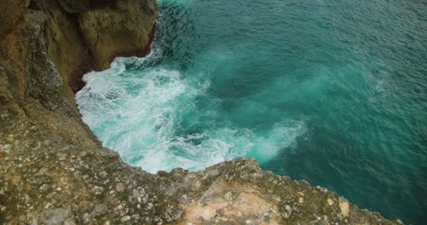 Top down view of turquoise water violently crashing against jagged dark coastal Stock-Footage 327792825