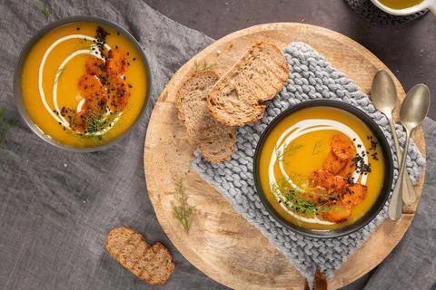 Top-down view of two bowls of vibrant orange carrot soup garnished with cre.. Foto stock