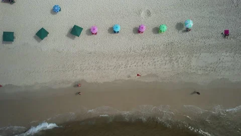 Top down view of two people walking on beach near colourful parasols Stock Footage 232245751
