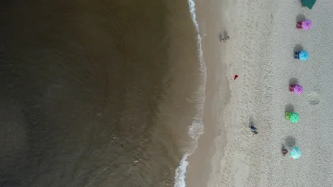Top down view of two people walking on beach near colourful parasols Stock Footage 232245781