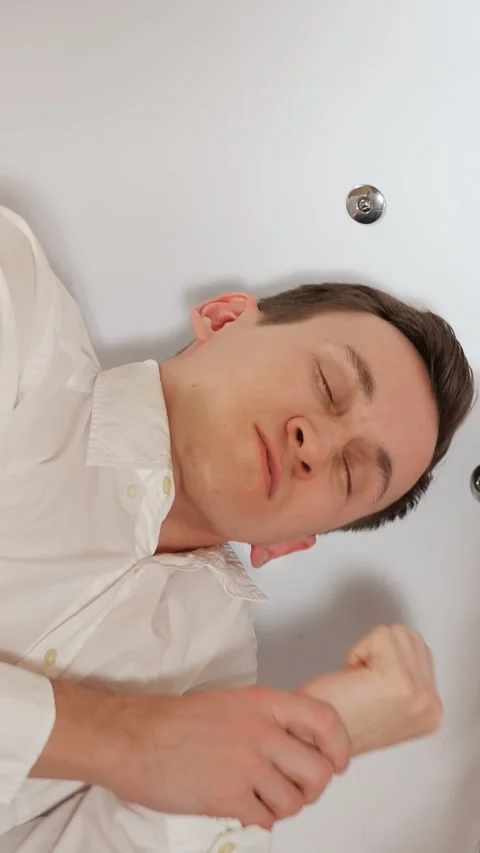 Top down view of an unconscious young man in a white shirt lying in a bathtub Video stock 341677274