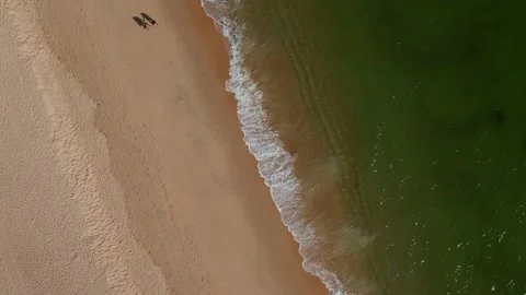 Top down view of unidentifiable couple holding hands walking along idyllic beach Stock Footage 195980833
