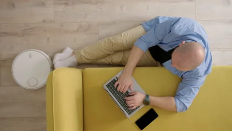 Top down view of unrecognizable bald man in blue shirt, sitting on floor next to Stock Footage 243775792