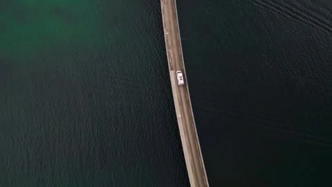 Top down view of vehicle drove across tiny bridge above the calm turqoise Stock Footage 275775243