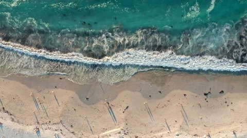 Top down view of vibrant blue waves breaking on a white beach at sunset Stock Footage 170724883