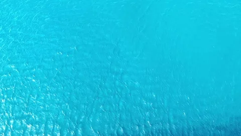 Top-down view of vibrant turquoise water with gentle ripples and sun reflections Vídeos de archivo 335046211