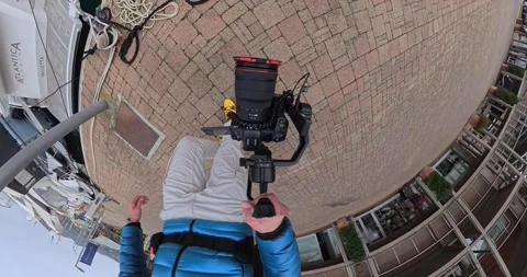 Top down view of videographer holding camera on gimbal at marina Stock Footage 336655781