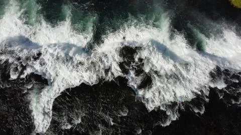Top-Down View of Waves on a Black Sand Beach Foto stock