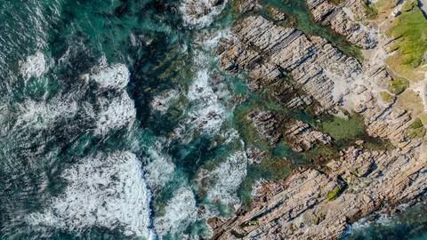Top Down View of Waves Breaking Across Rocky Coastline Stock Photos