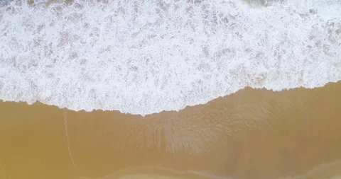 Top down view of waves crashing onto golden beach from above aerial 4K Video stock 87572917