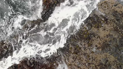 Top down view of waves crashing on the rocks and turquoise water. 4K 24FPS. Stock Footage 132366507