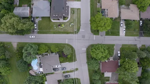 Top down view of white car driving through suburban neighborhood. Aerial Stock Footage 199003426