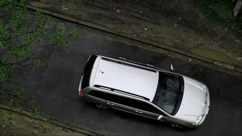 Top-down view of a white car driving on wet asphalt in the spring rain. Food and Stock Footage 276182978