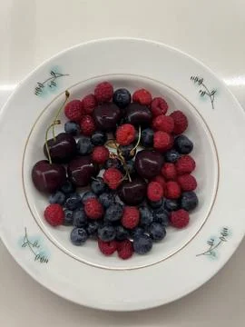 A top-down view of a white ceramic plate containing fresh berries Stock Photos