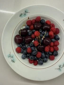 A top-down view of a white ceramic plate containing cherries Stock Photos