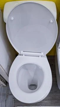 Top down view of a white ceramic toilet with open lid in a bathroom setting.. Stock Photos