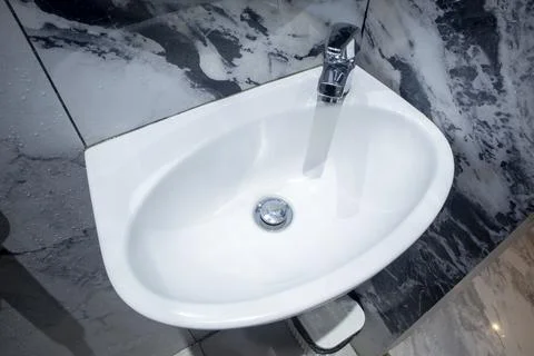 A top-down view of a white ceramic wall-mounted bathroom sink featuring a c.. Stock Photos