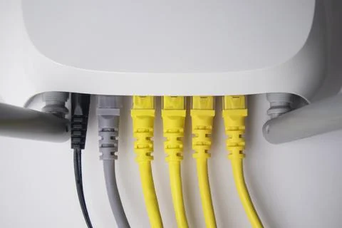 Top-down view of white router with four yellow Ethernet cables Stock Photos