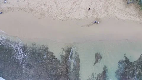 Top down view of white sand beach full of human footprints with rocks and wav Stock Footage 239621167
