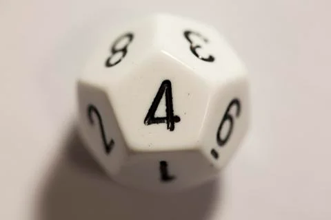 Top-down view of a white twelve sided die, showing a four 스톡 사진