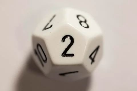 Top-down view of a white twelve sided die, showing a two 스톡 사진