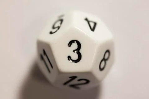 Top-down view of a white twelve sided die, showing a three 스톡 사진