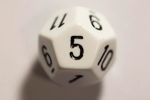 Top-down view of a white twelve sided die, showing a five 스톡 사진