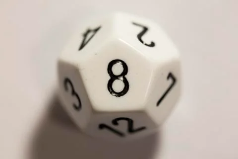 Top-down view of a white twelve sided die, showing an eight 스톡 사진