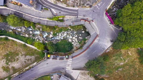 Top-down view of a winding mountain road intersection beside a rocky stream Stock Footage 346940559