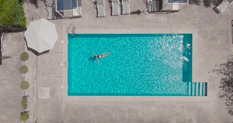 Top down view of a woman in blue swimsuit lying on her back in the pool. Stock-Footage 252242504