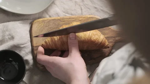 Top down view of woman chef cuts croissant. Appetizing pastries are on a cutting Stock Footage 150407801