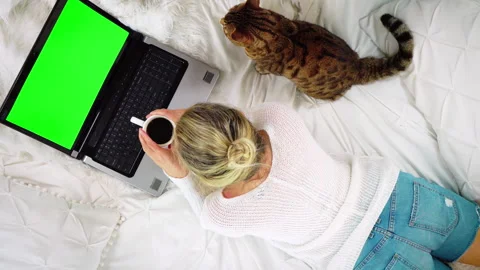 Top-down view of woman lying on bed looking at blank green screen of laptop Vídeos de archivo 150841690
