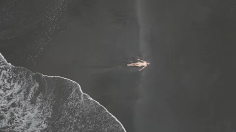 Top down view of woman lying on volcanic black sand beach in Bali, Indonesia Stock Footage 308231992