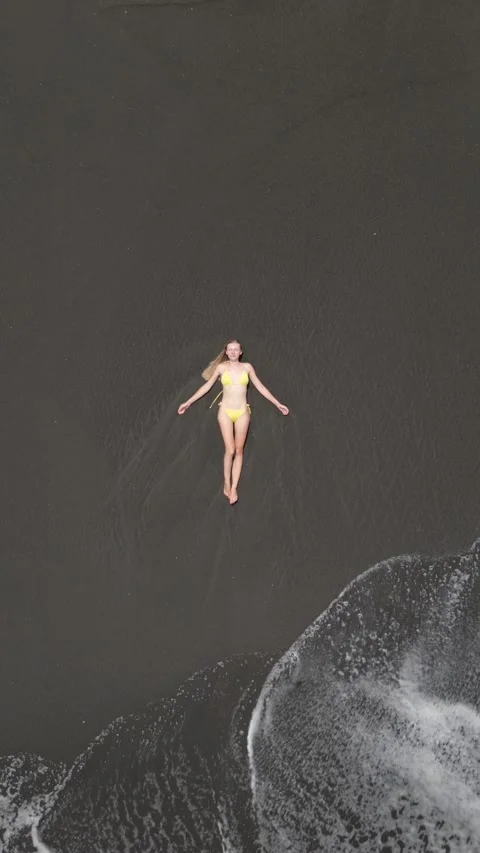 Top down view of woman lying on volcanic black sand beach in Bali, Indonesia Stock Footage 312817044